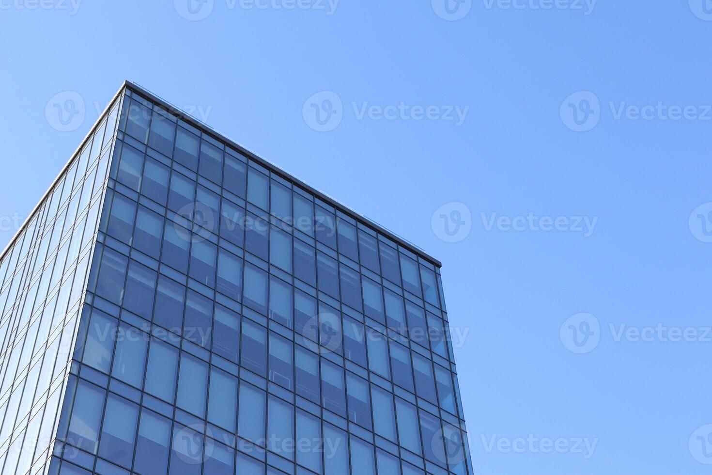 A Modern Glass Building Stands Tall Against a Clear Blue Sky Adding to Urban Aesthetics photo