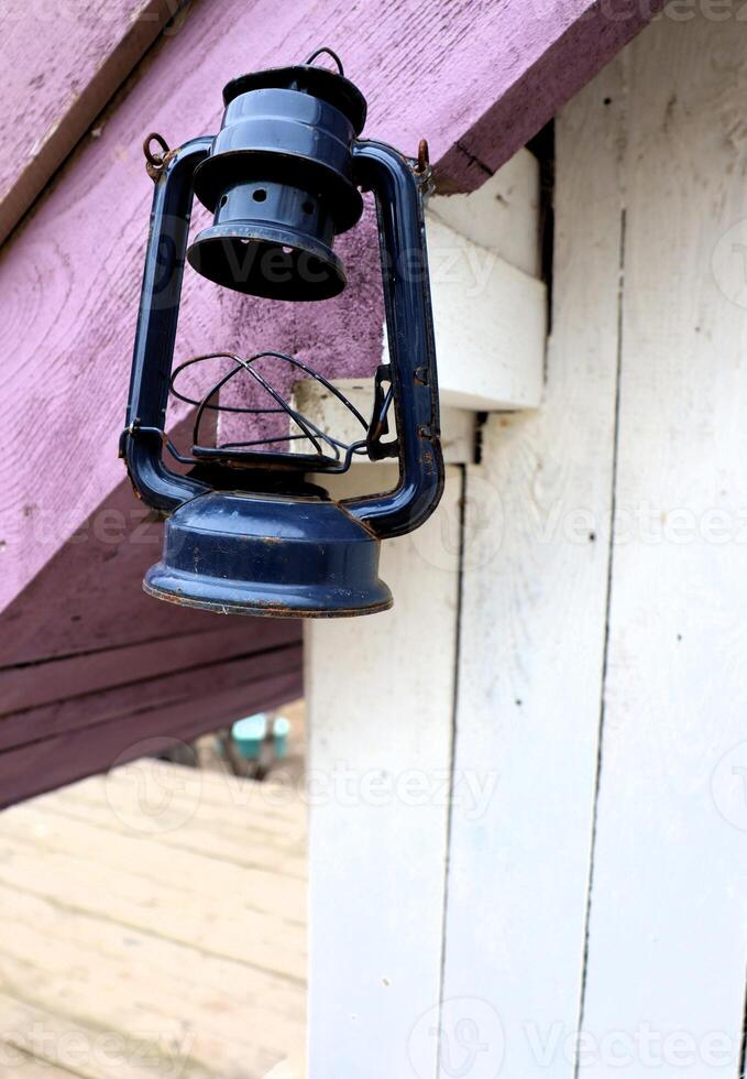 A classic black lantern hangs on a rustic porch, creating a warm ambiance for the cabin photo