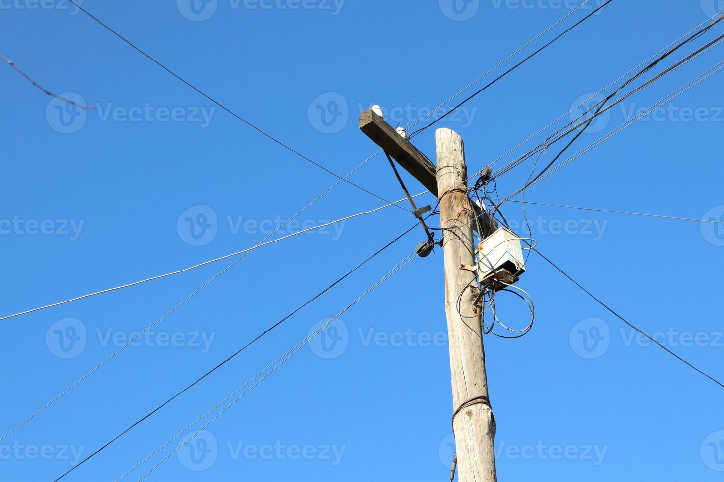 A Wooden Utility Pole Standing Tall Against a Clear and Beautiful Blue Sky Above photo
