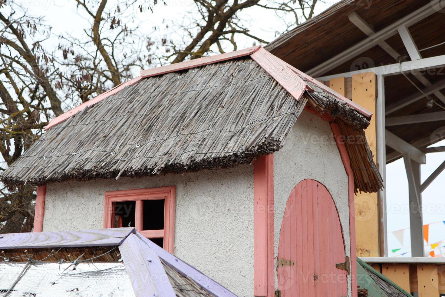 A Charming Playhouse featuring a Thatched Roof along with delightful Pink Accents photo