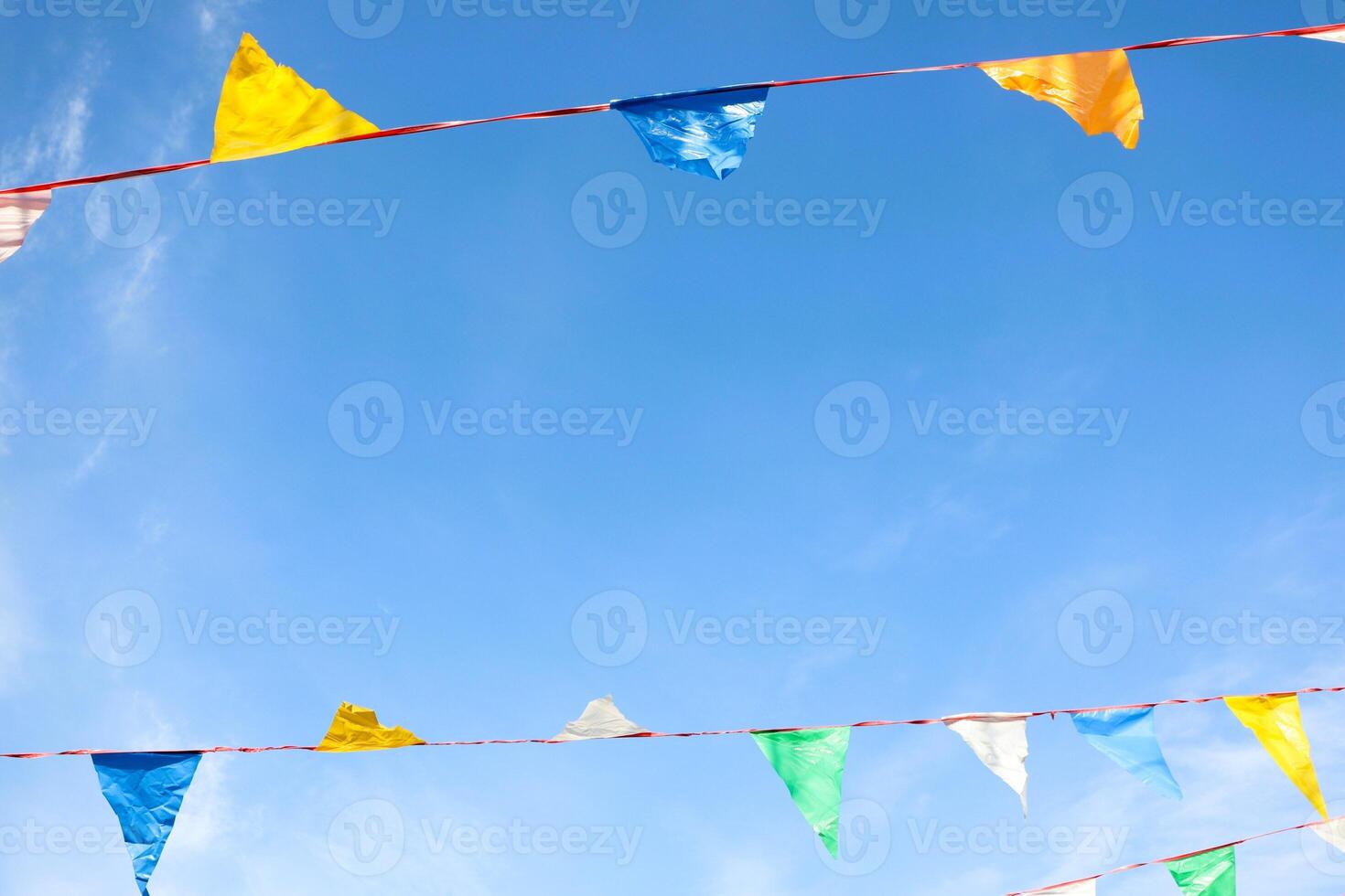 Vibrant and Colorful Festival Bunting Hanging Beautifully Against a Bright Blue Sky Above photo
