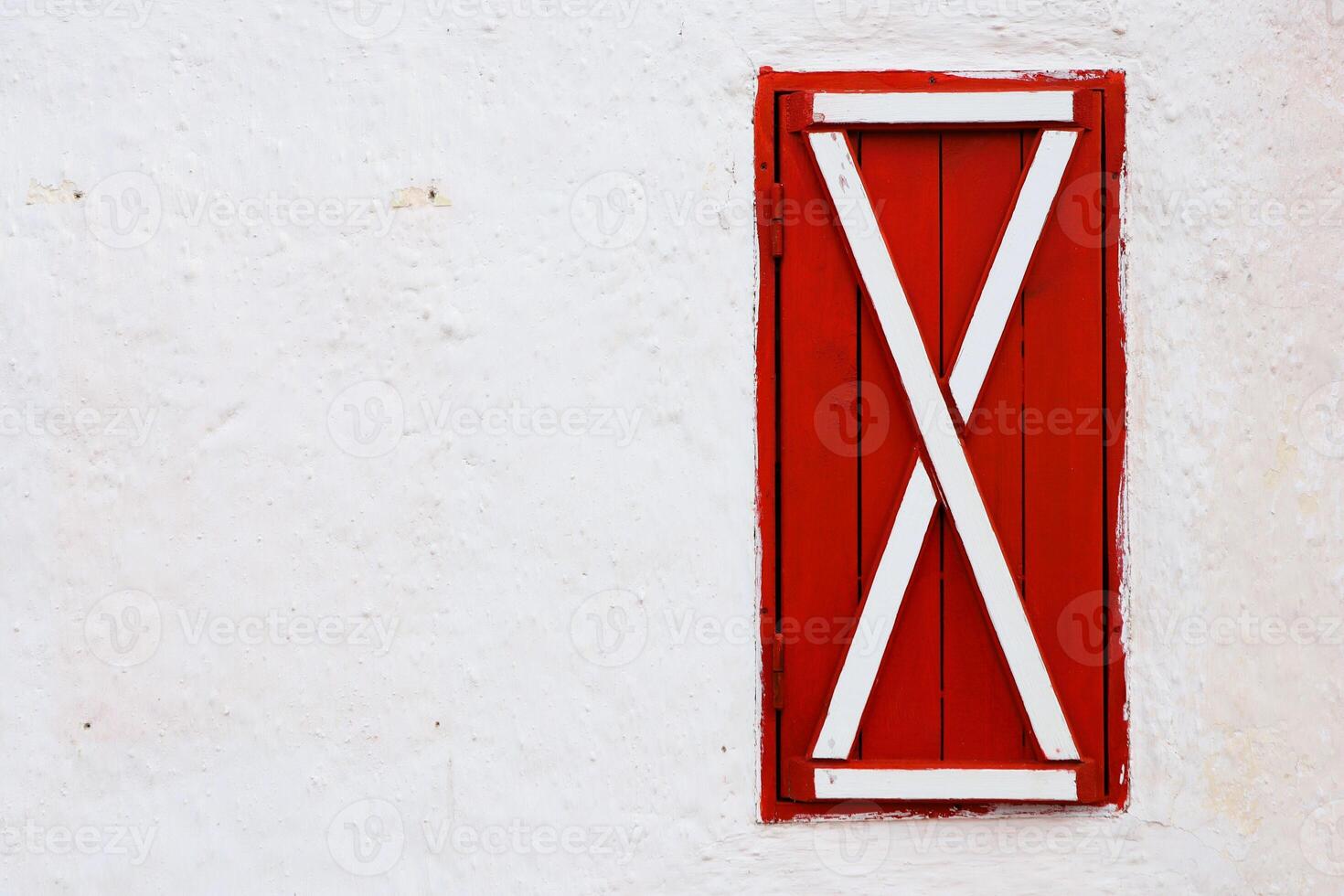 The bright and vibrant red shutter beautifully graced by an elegant white wall structure photo