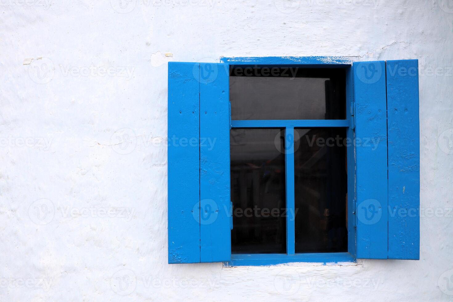 A Charming Blue Window with Shutters set against a Bright White Wall, creating a delightful scene photo