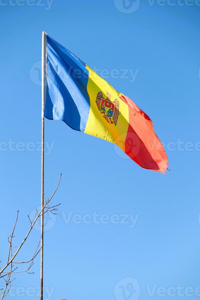 The Vibrant Flag of Moldova Waves Proudly Against a Clear, Beautiful Blue Sky Above photo