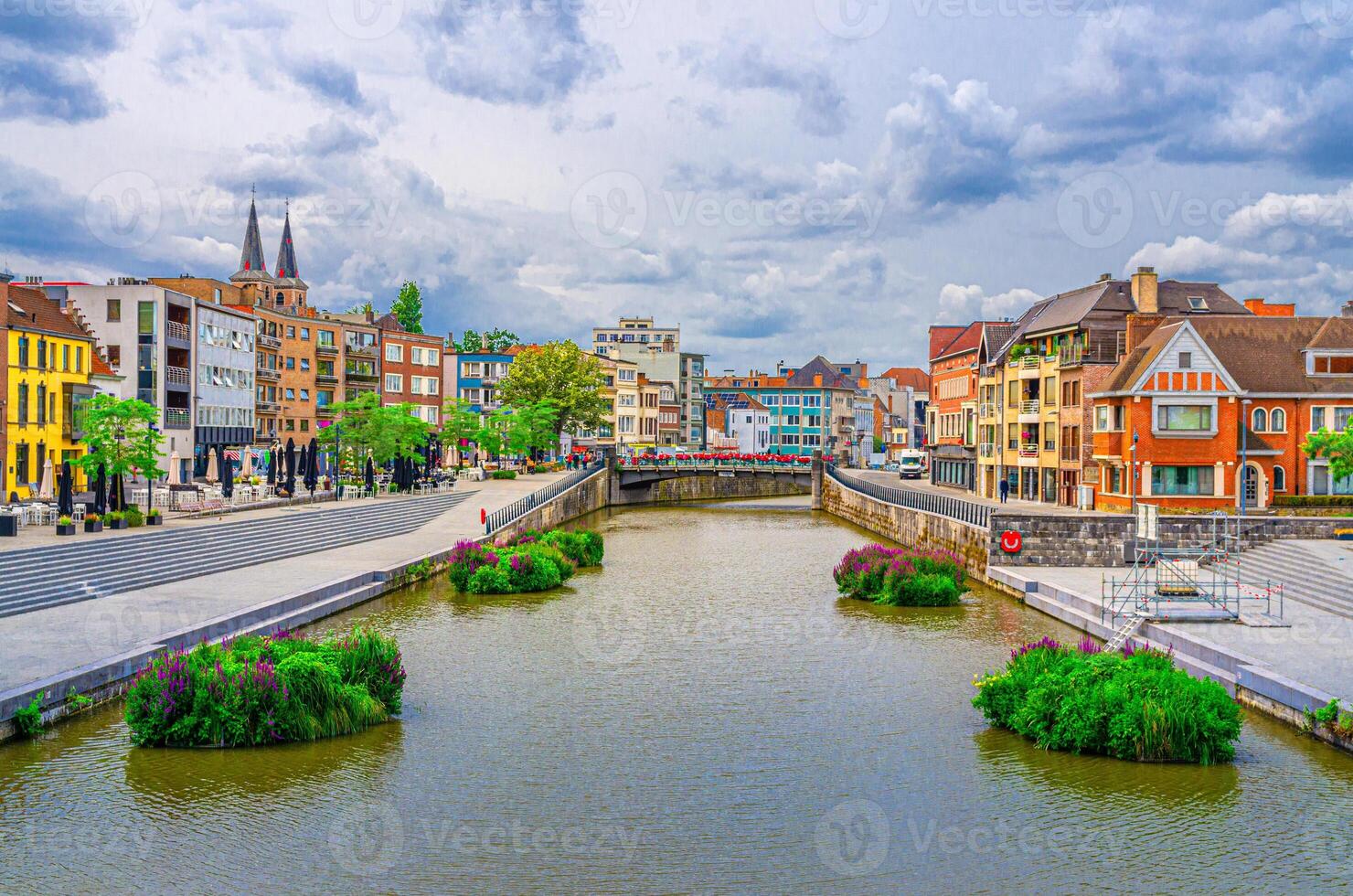 Kortrijk cityscape with embankment of Lys river, bridge across Leie river, plants in water and modern buildings in historical centre, belgium landmark, West Flanders province, Flemish Region, Belgium photo
