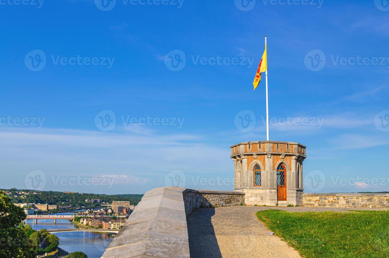 Small tower with Walloon flag on Citadel of Namur Citadelle de Namur stone fortress on hill in historical city centre, Meuse river with bridges background, Wallonia, Walloon Region, Belgium photo