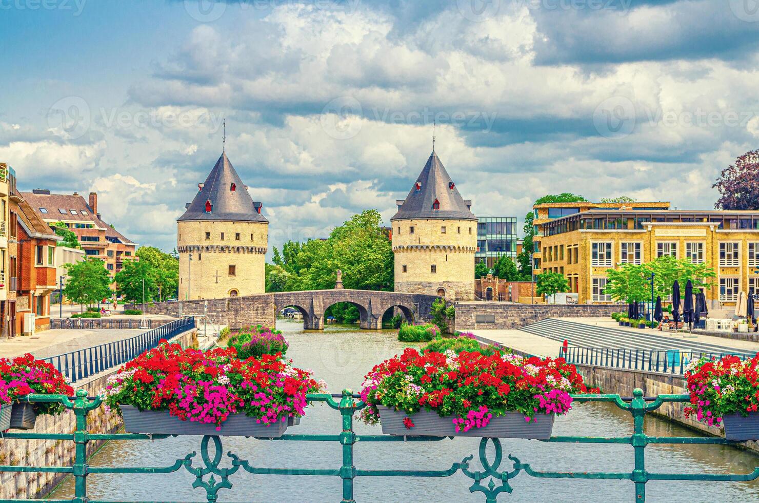Kortrijk cityscape with Lys river, Broel Towers Gothic style buildings and Bridge in historical centre, red flowers on bridge fence, Fortification towers, belgium landmark, Flemish Region, Belgium photo