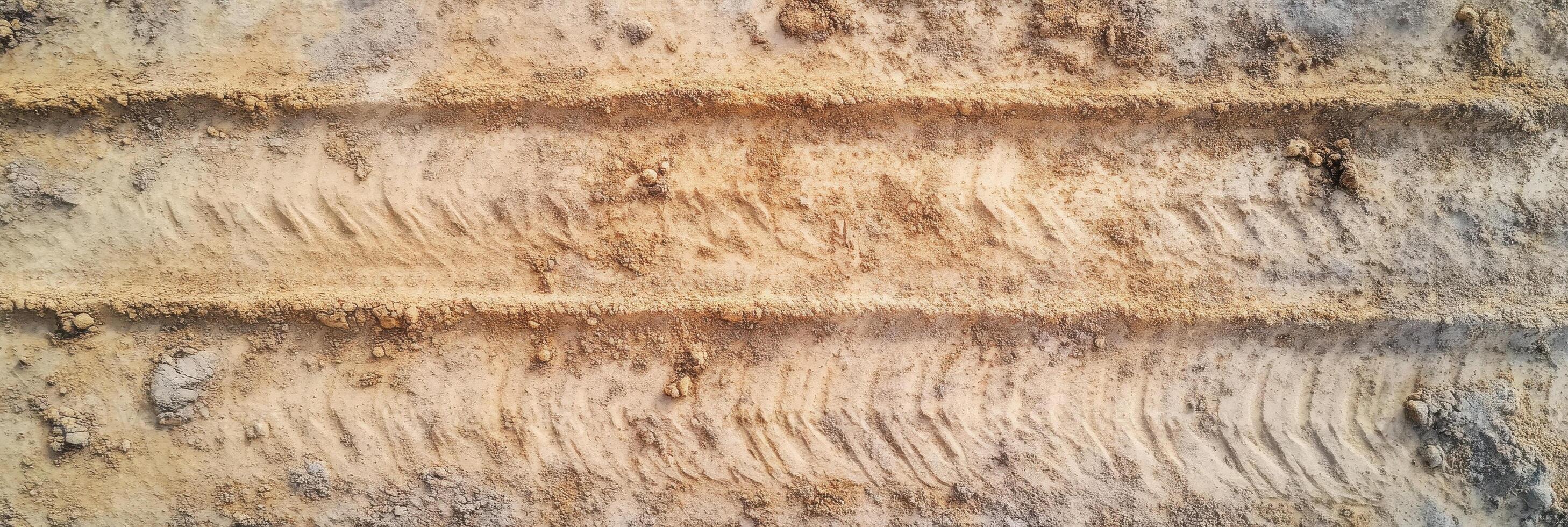 Aerial view of tire tracks on sandy ground surface texture with earth tones photo