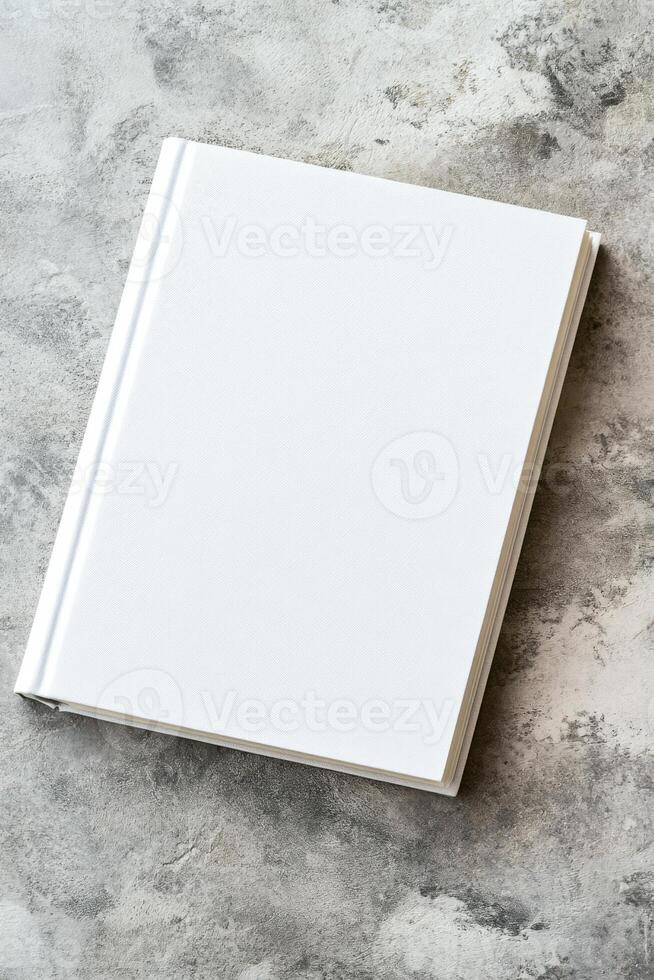 Minimalist book with blank cover placed on textured concrete surface for creative design mockup photo