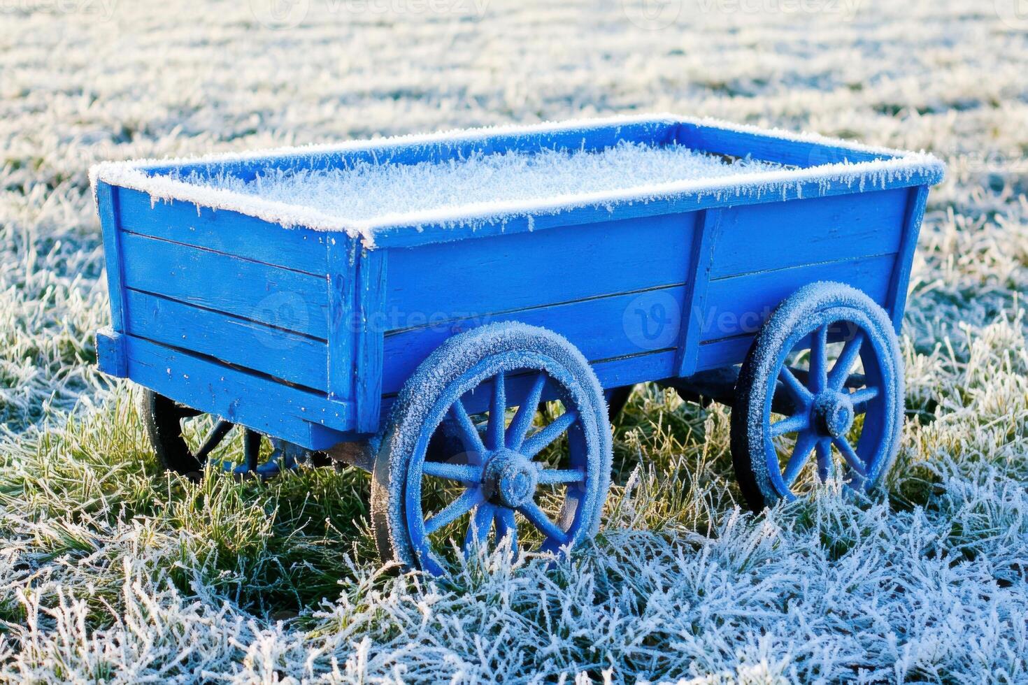 Vintage wagon in faded blue paint rests in frost-covered grass during a cool morning, showcasing rustic charm and timeless beauty photo