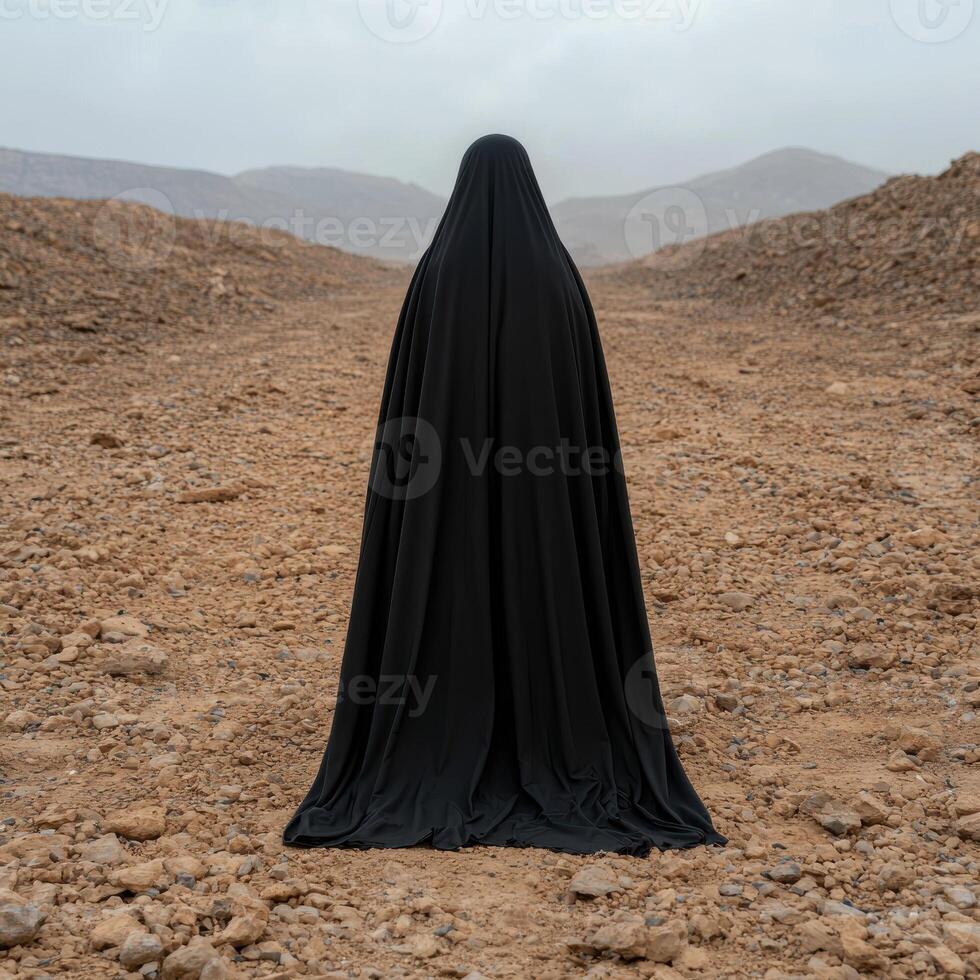 A mysterious figure in black robe standing in desert landscape photo