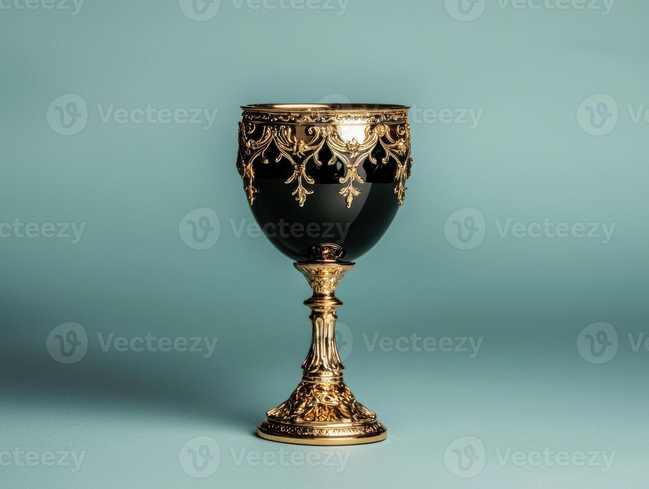 Ornate golden goblet with black bowl on a teal background photo