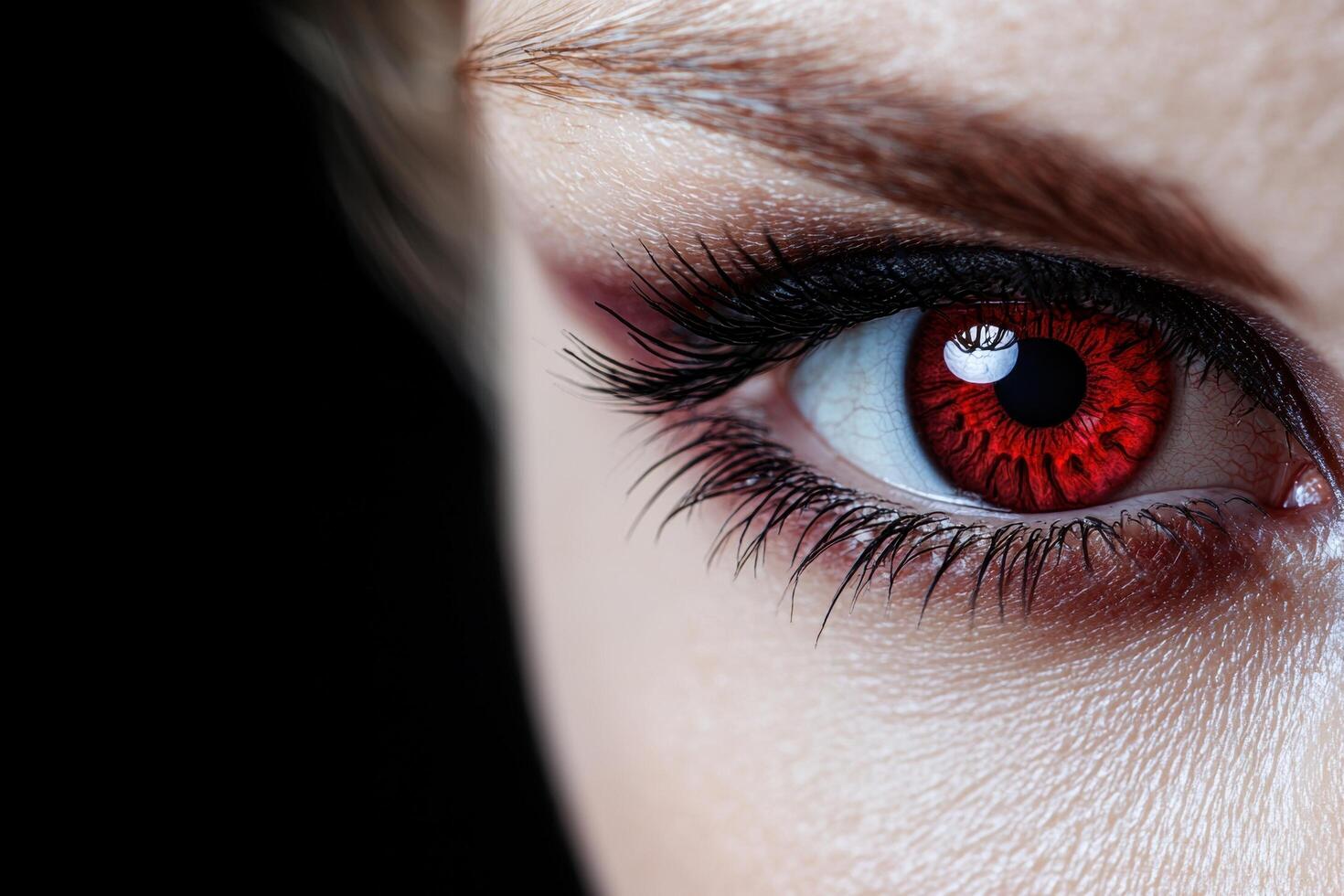 Closeup of a womans eye with red iris and dark makeup photo