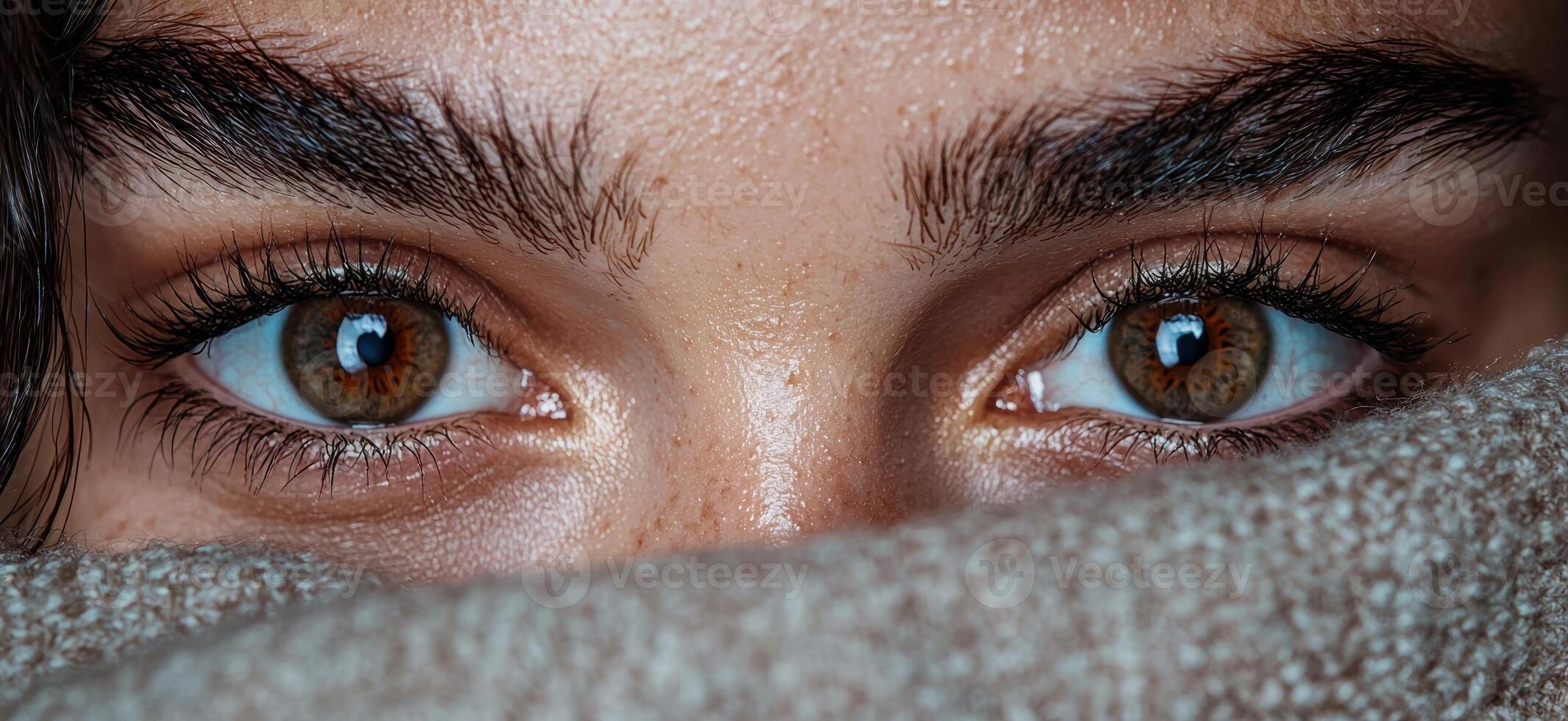 Closeup of a womans eyes peering over a soft textile photo