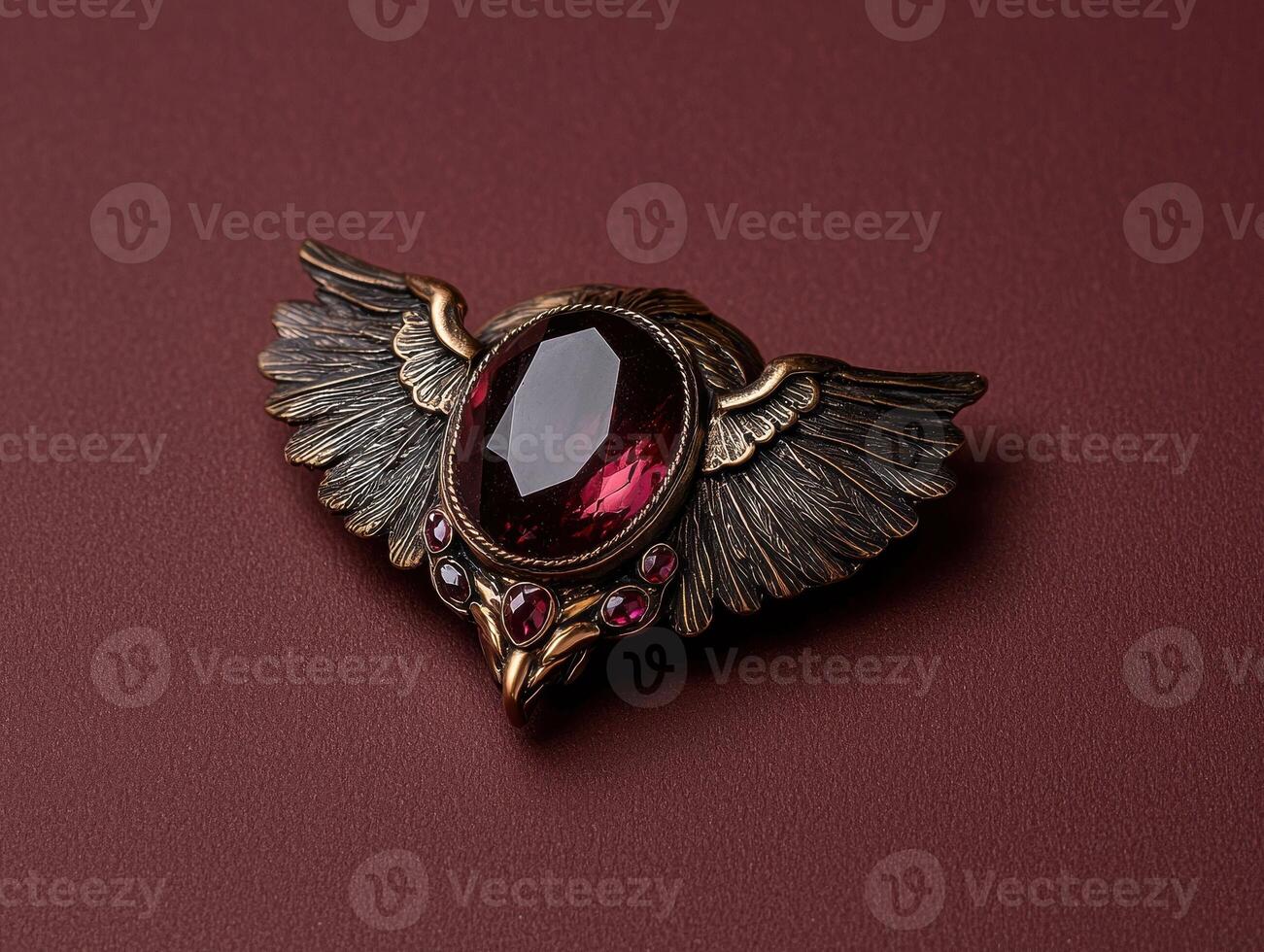Ornate winged brooch with a deep red gemstone photo