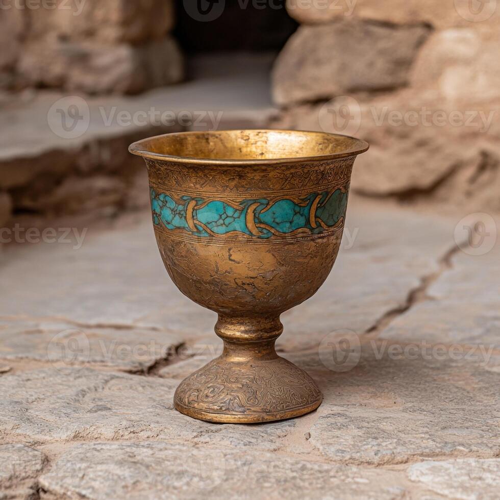 Antique golden chalice with turquoise inlay on stone surface photo
