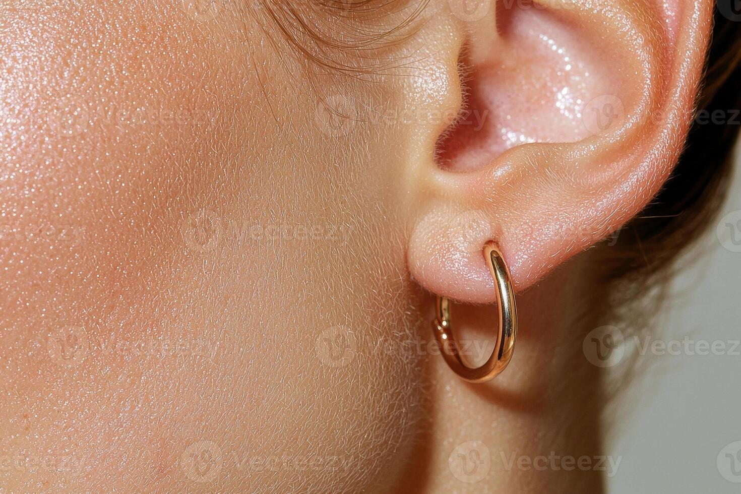 Close up of a womans ear with gold hoop earrings photo