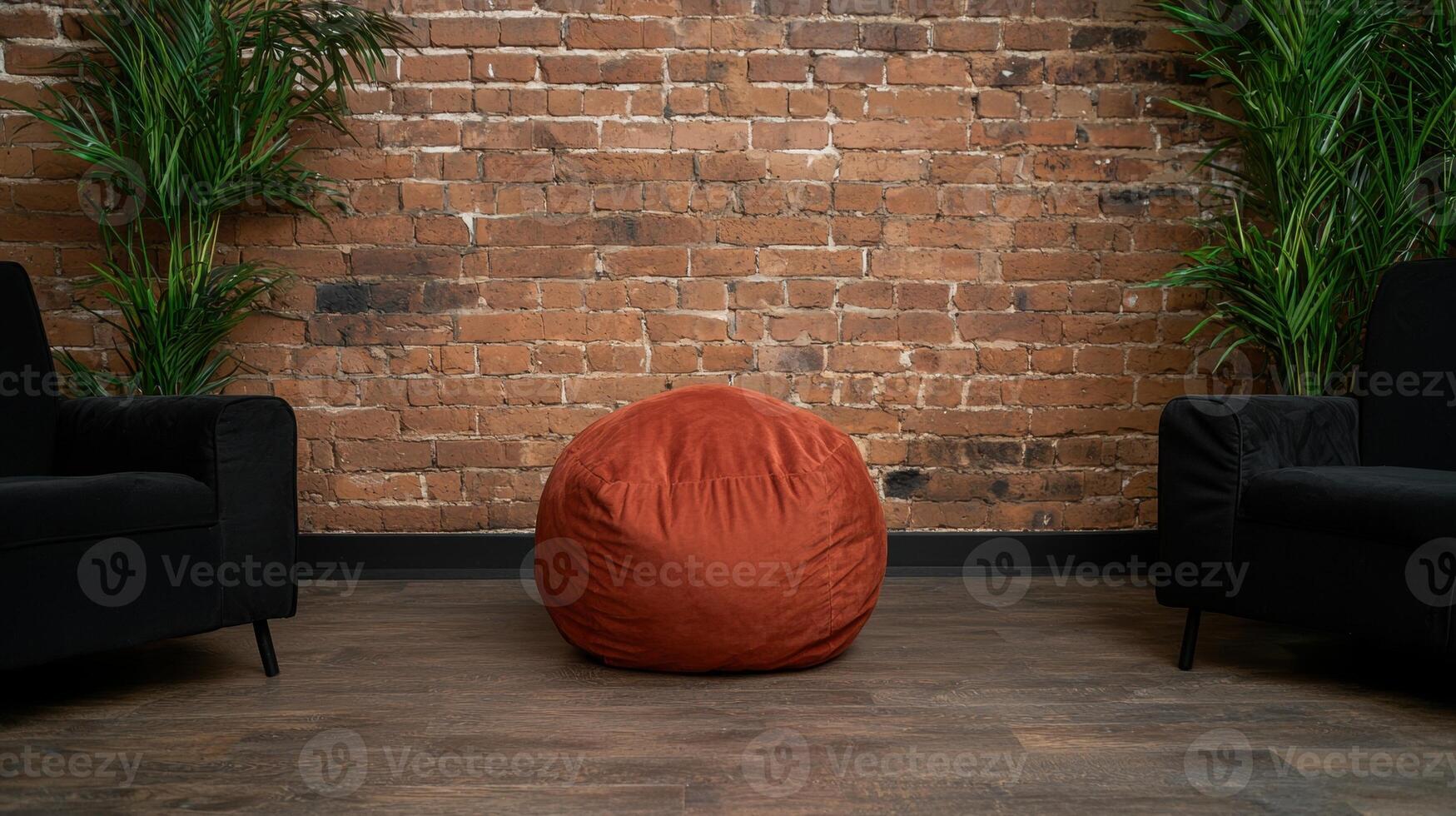 Red beanbag chair in front of a brick wall photo
