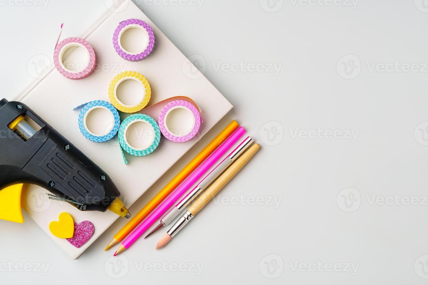 Crafting supplies arranged for creative projects with glue gun, decorative tape, and colorful pencils photo
