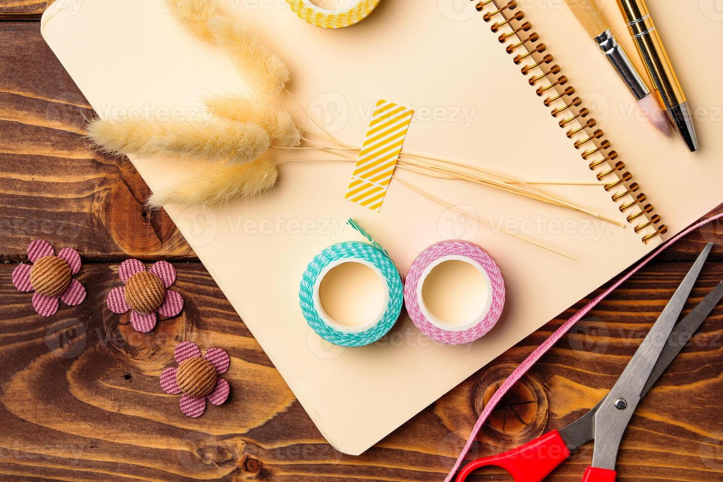 Crafting materials arranged on a wooden table along with a notebook and scissors for creative projects photo