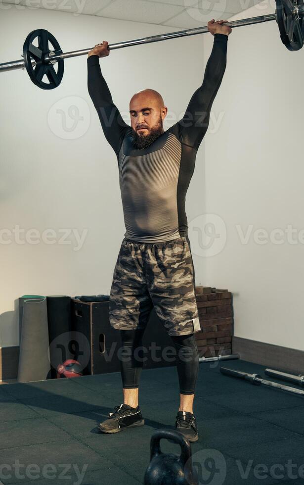 Man lifting weights in gym during strength training session focusing on upper body development and fitness improvement photo