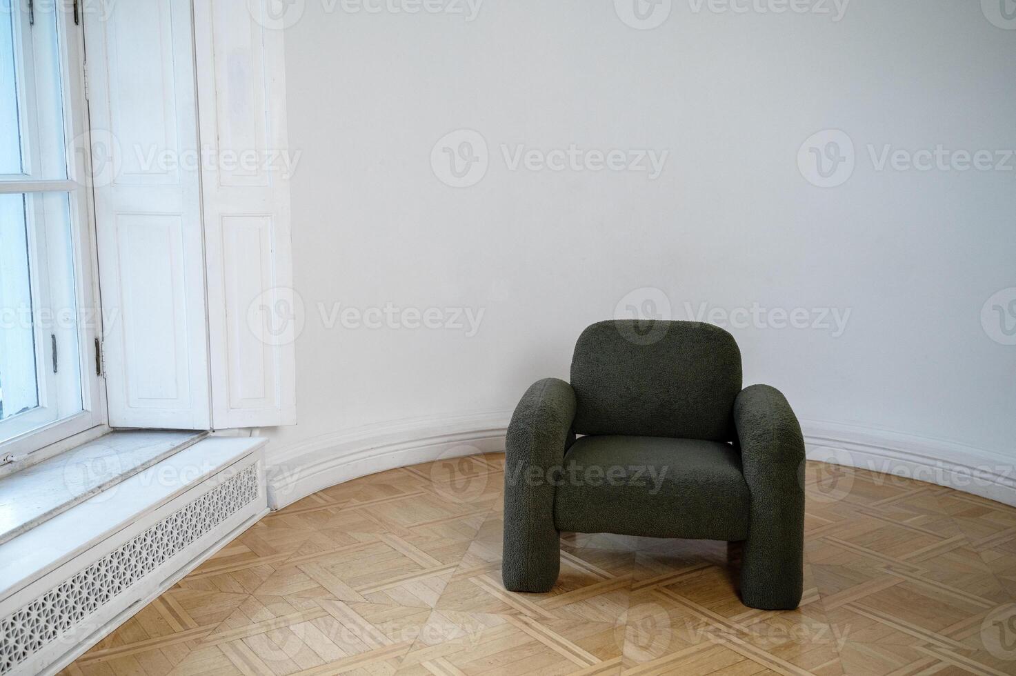 A chair sitting in a room. High quality photo,A dark gray minimalist armchair stands in the room. A beautiful wooden floor. There is warm-colored parquet on the floor. daylight from large window photo