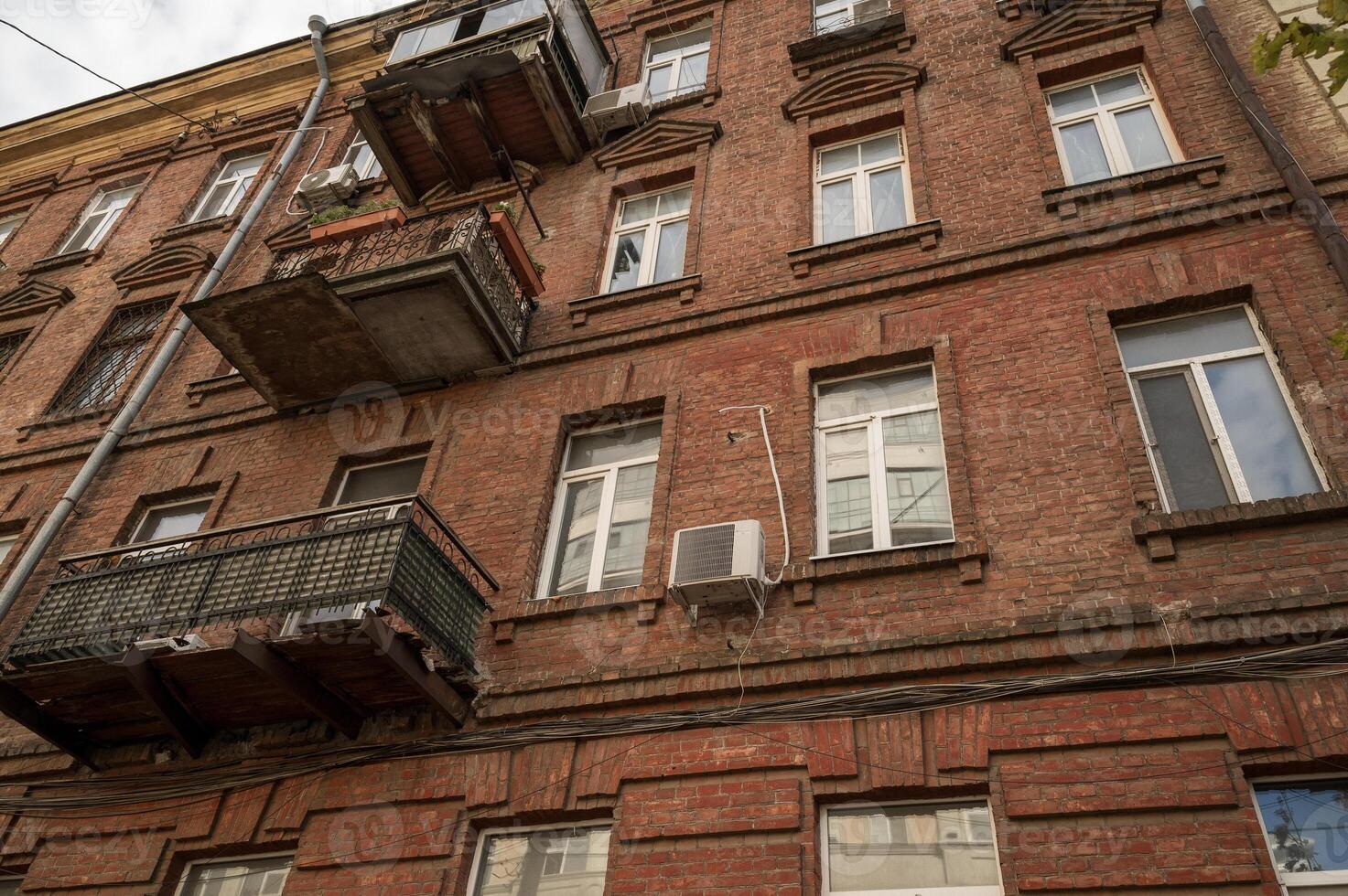 A large brick building. High quality photo, wall of a nineteenth century red brick residential building. residential building with plastic windows and air conditioning. photo