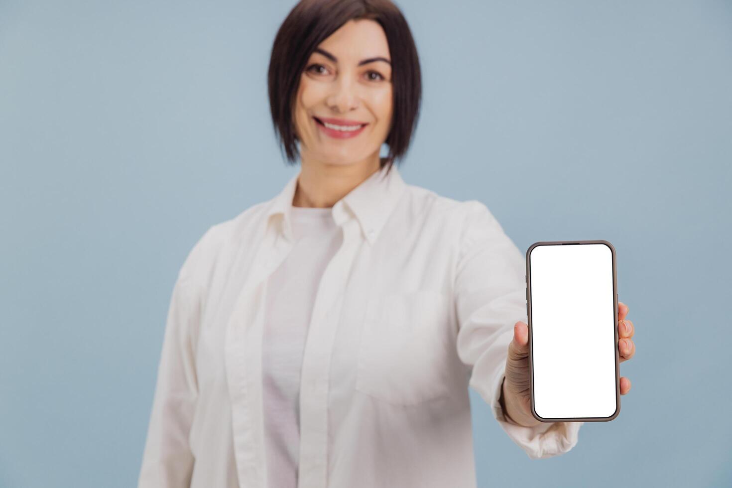 Smiling businesswoman showing smartphone with blank screen on blue background photo