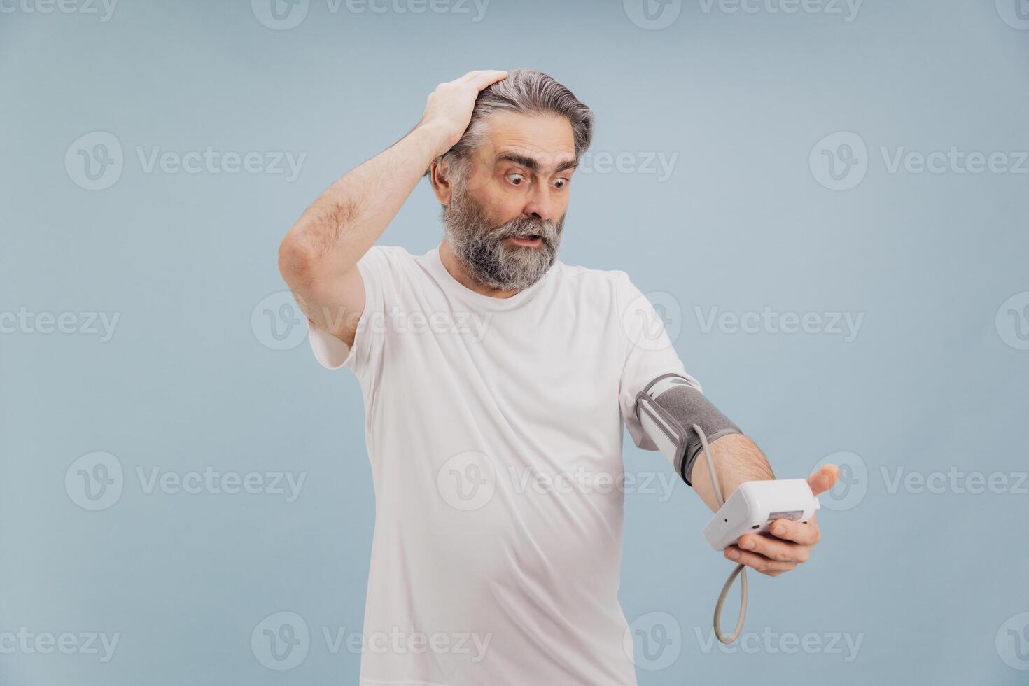 Shocked senior man checking blood pressure with digital monitor photo