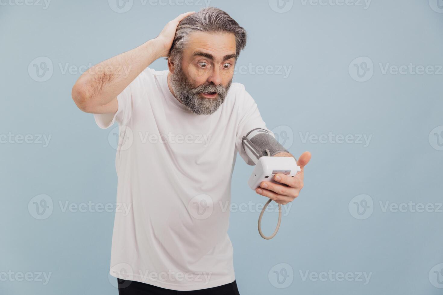 Shocked senior man checking blood pressure with automatic sphygmomanometer photo