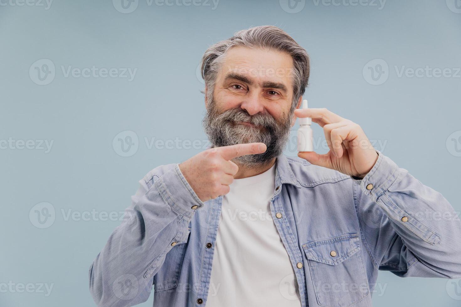 Senior man holding nasal spray and pointing on it photo