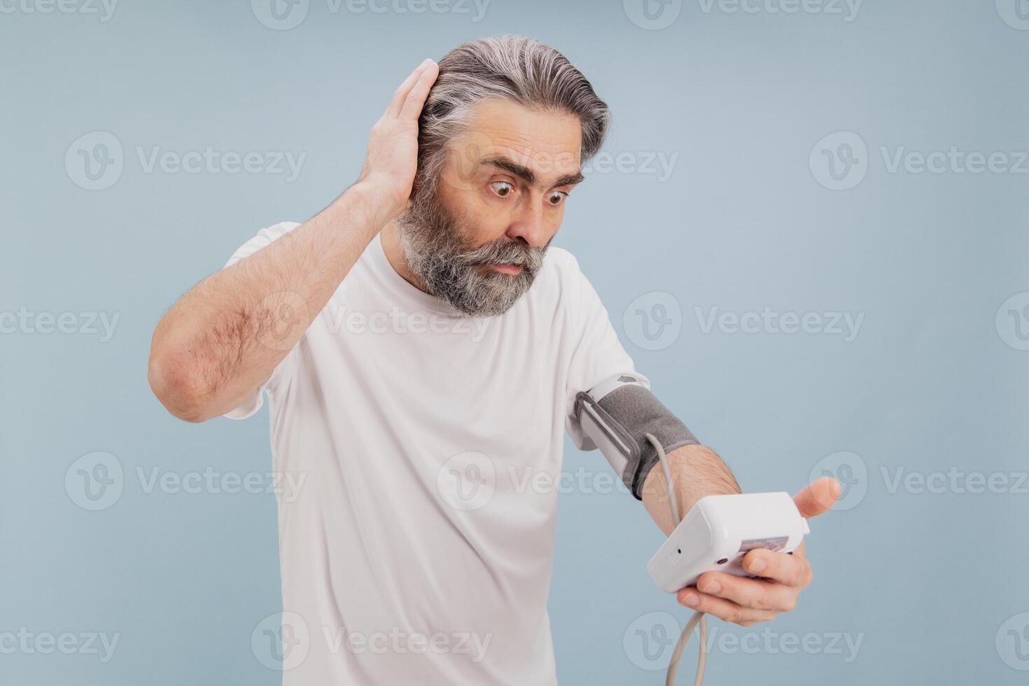 Shocked Senior Man Checking Blood Pressure with Electronic Device photo