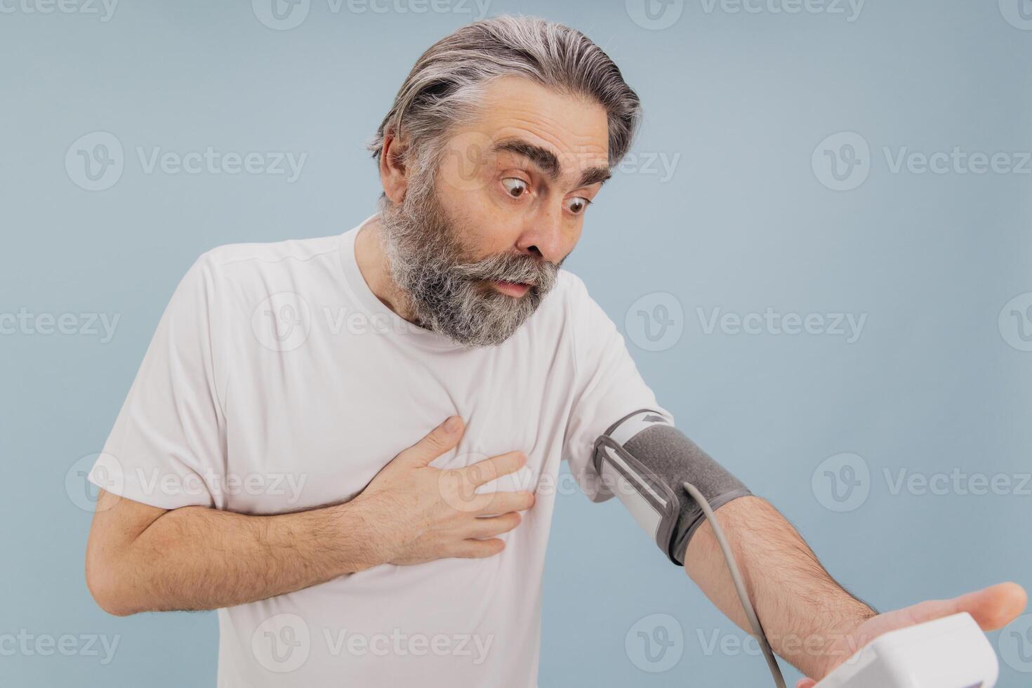 Shocked senior man checking blood pressure with sphygmomanometer, suffering chest pain photo