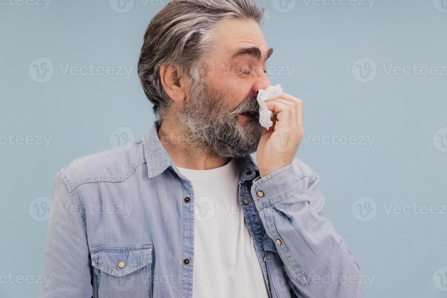 Senior man blowing his nose with tissue suffering from illness photo