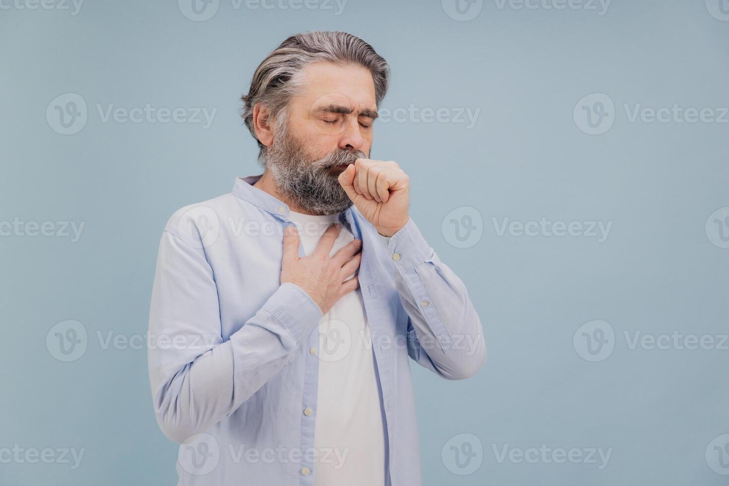Senior man suffering from cough and chest pain on blue background photo