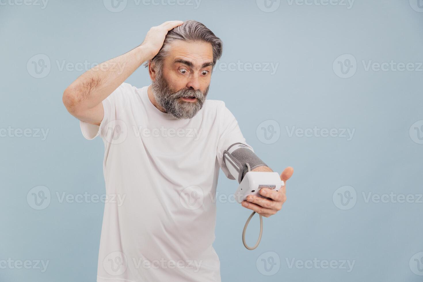 Shocked senior man checking blood pressure with electronic tonometer photo