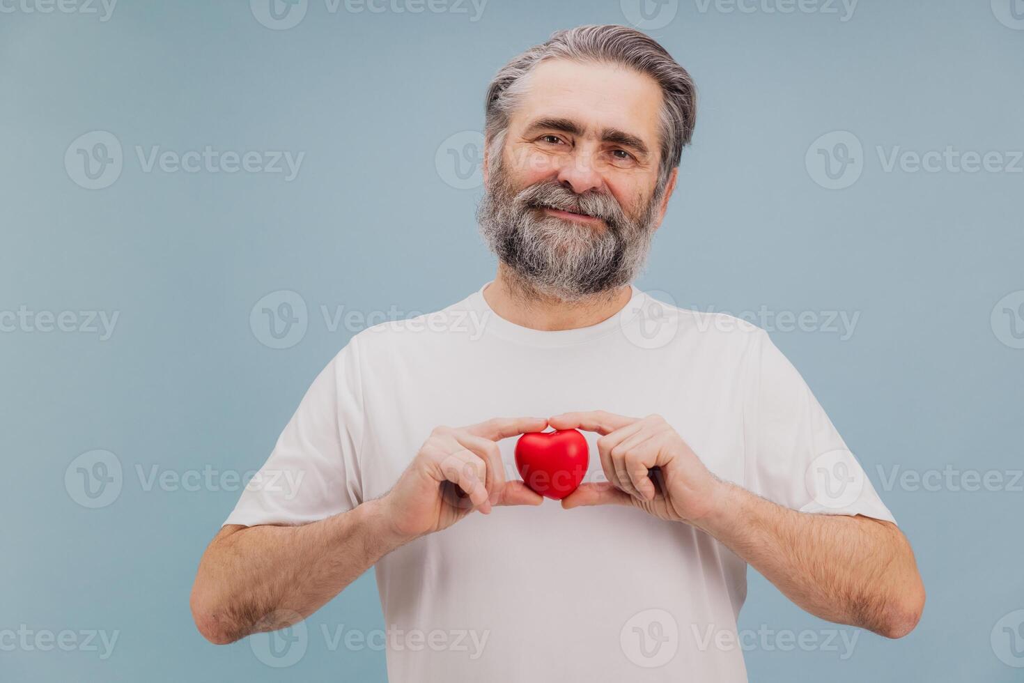 Smiling senior man holding red heart promoting heart health and healthcare photo
