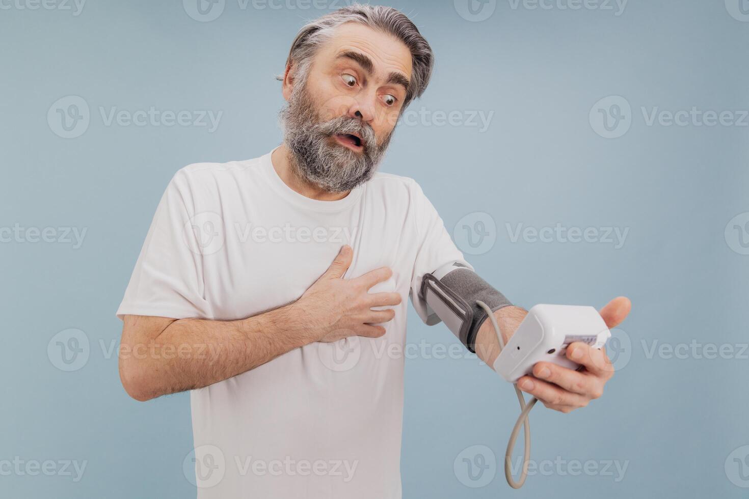 Shocked senior man checking blood pressure with portable medical device photo