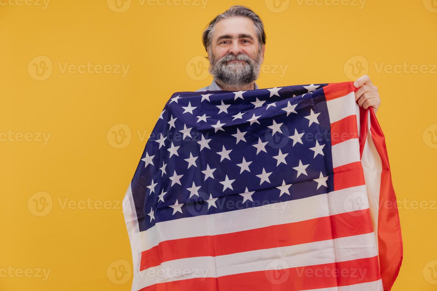 Patriotic senior man holding United States flag on yellow background photo