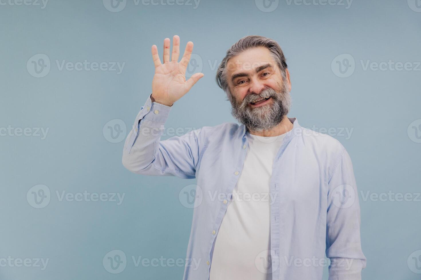 Smiling Senior Man Waving Hand on Blue Background photo