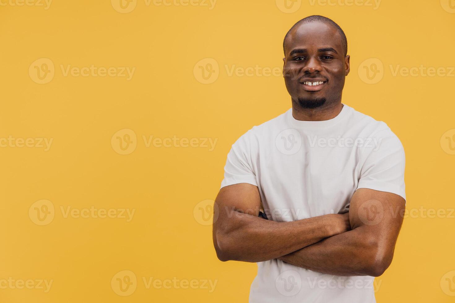 Confident young african american man smiling with arms crossed on yellow background photo