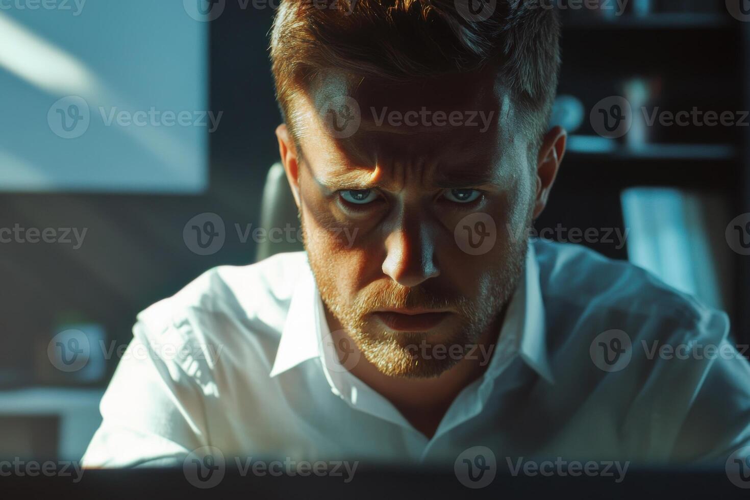 Focused man working late at a computer in a dimly lit office during the evening hours photo
