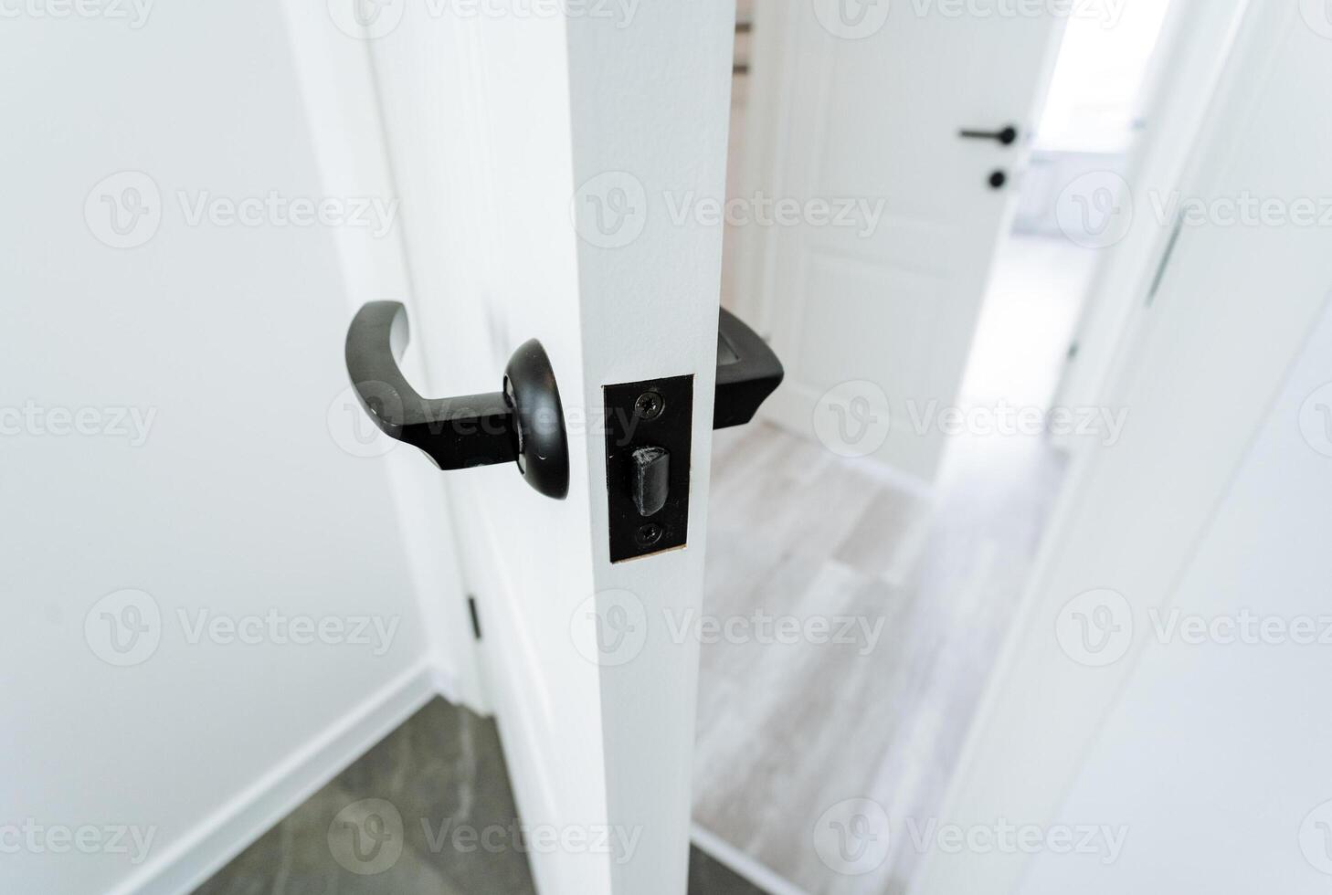 A black handle on a door handle in a white room photo