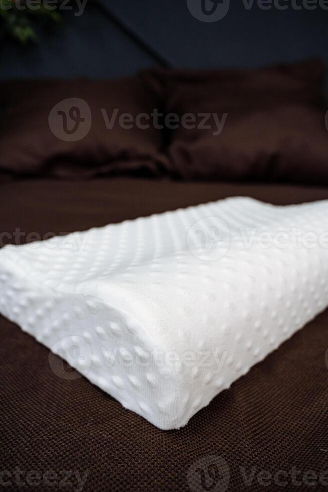 A white pillow on a bed with brown pillows photo
