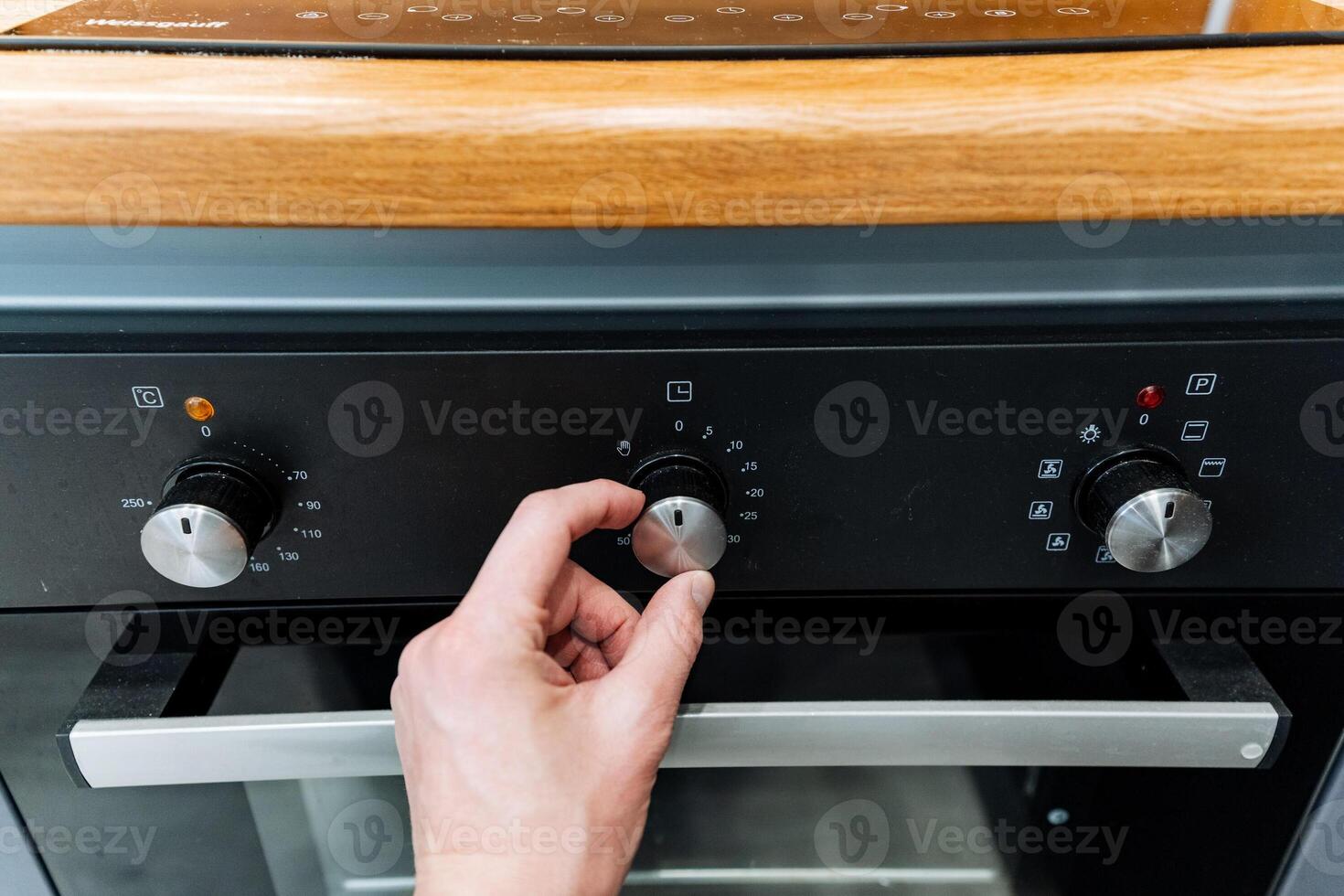 A person is turning the knob on an oven photo
