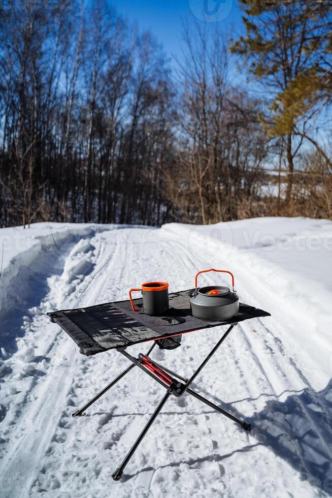 A camping table with two cups on it in the snow photo