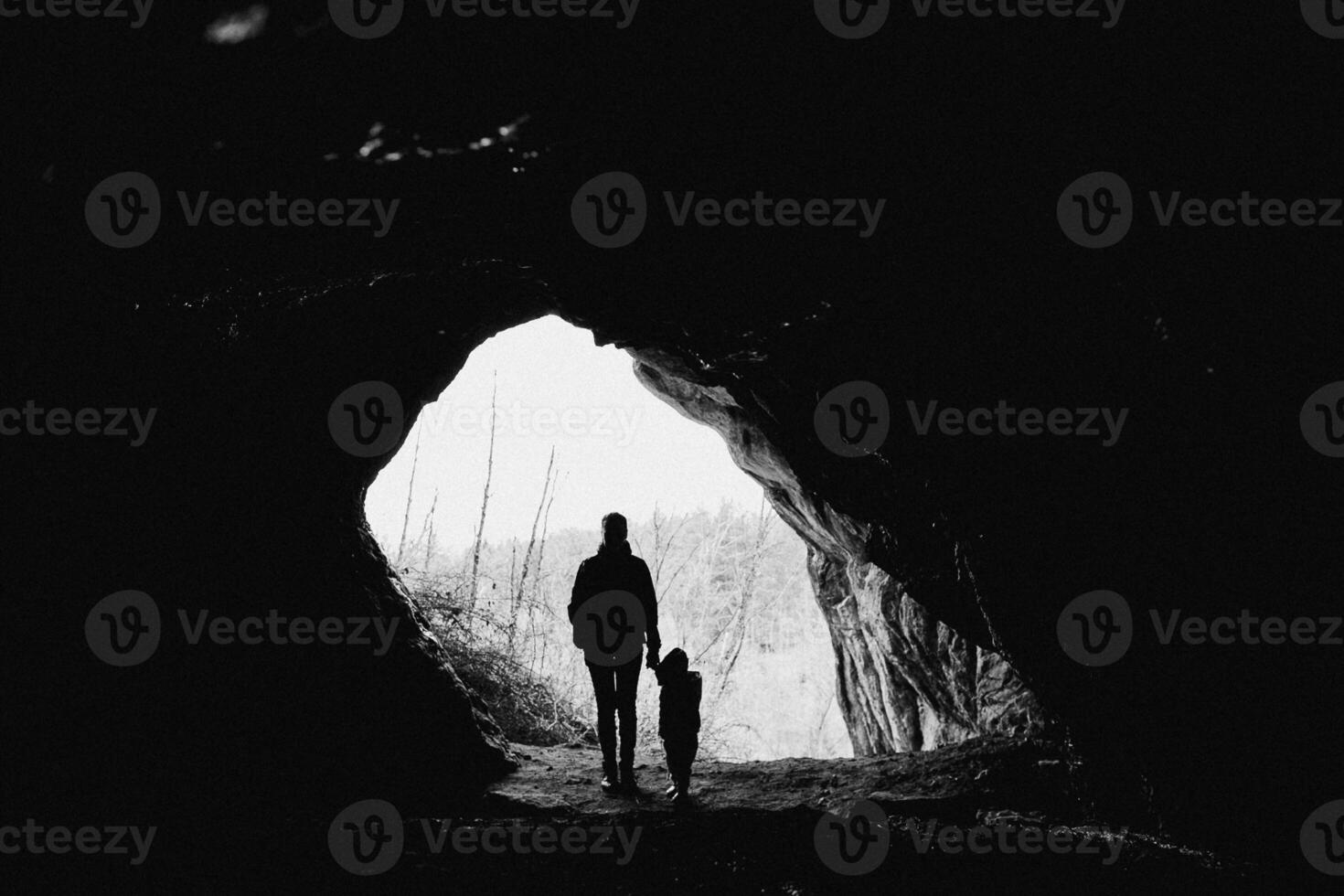 A man and child are standing in front of a cave photo