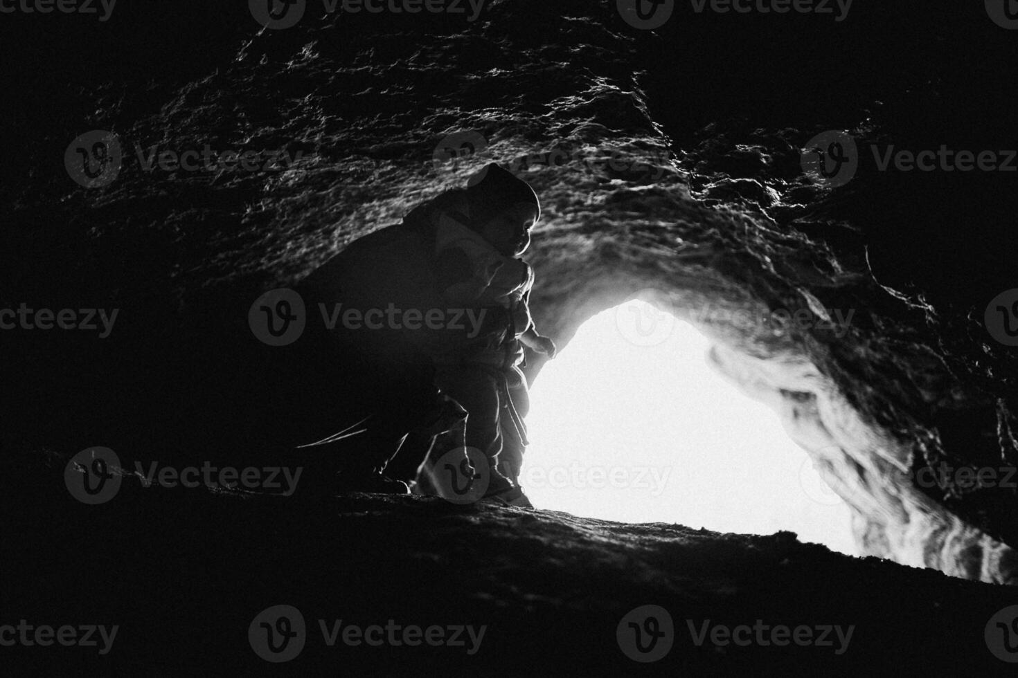 A person standing in a cave with the sun shining through photo