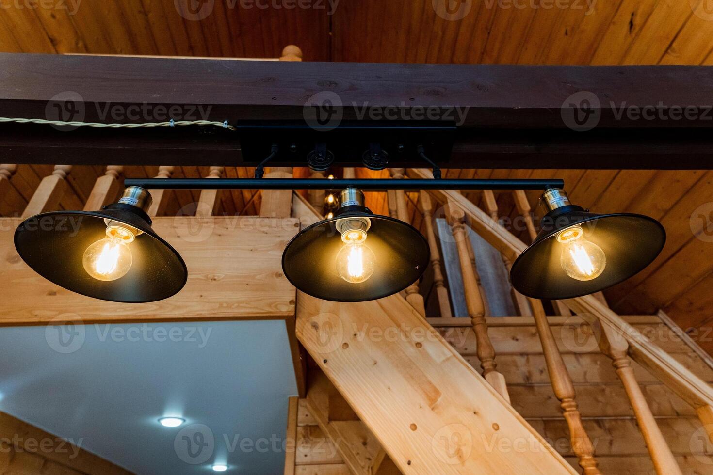 Three light bulbs hanging from the ceiling of a wooden staircase photo