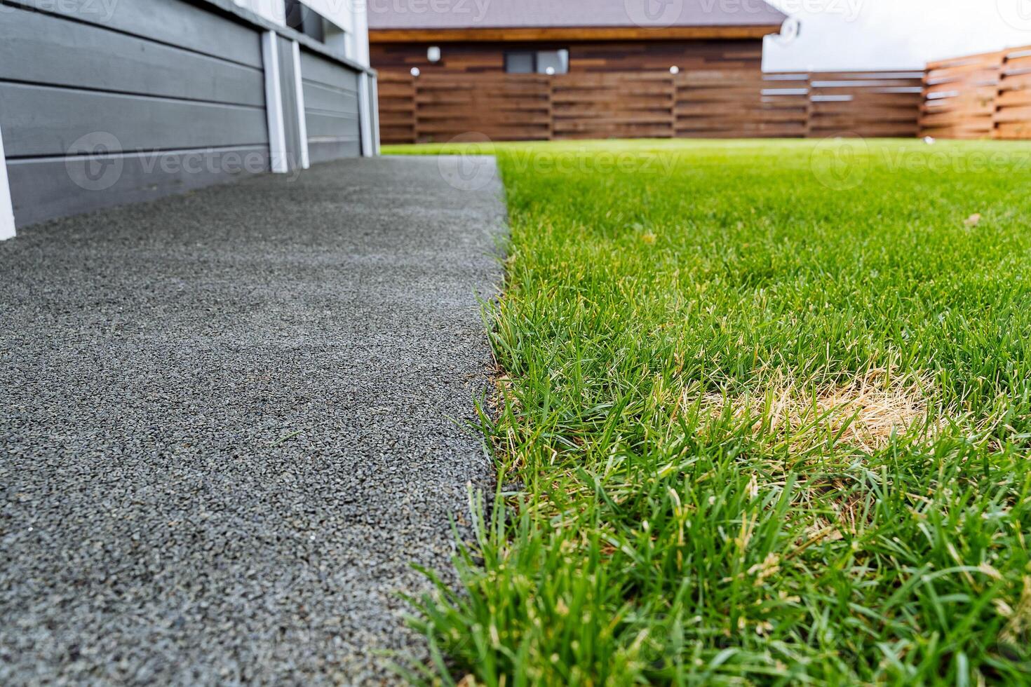 A grassy area with a sidewalk and a house photo